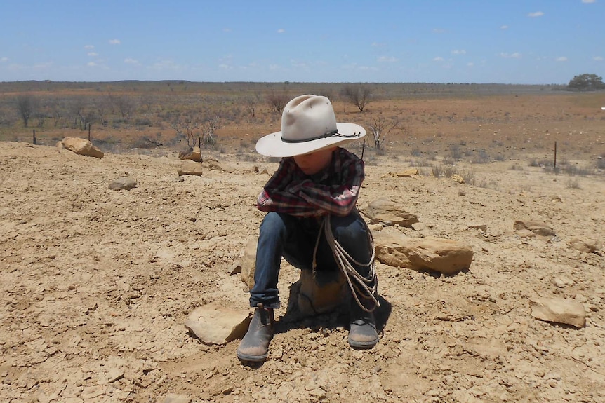 A boy sitting on drought affected land in central-west Queensland