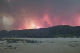 Flames leap behind a Nelson Bay shack