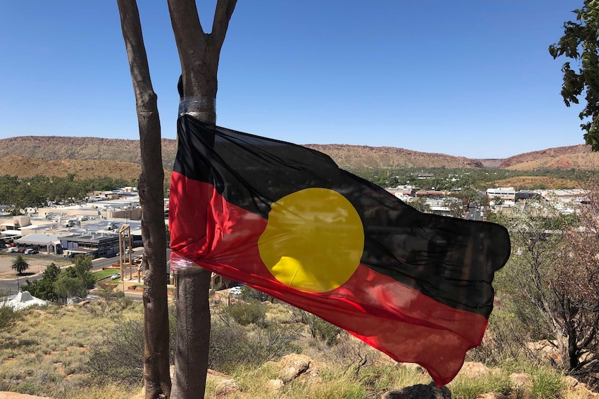 An Aboriginal flag is stickytaped to a tree on top of Anzac Hill in Alice Springs.