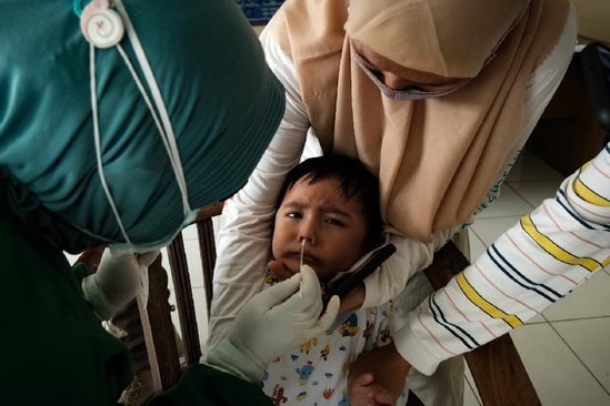 A kid is getting a swab test through his nose