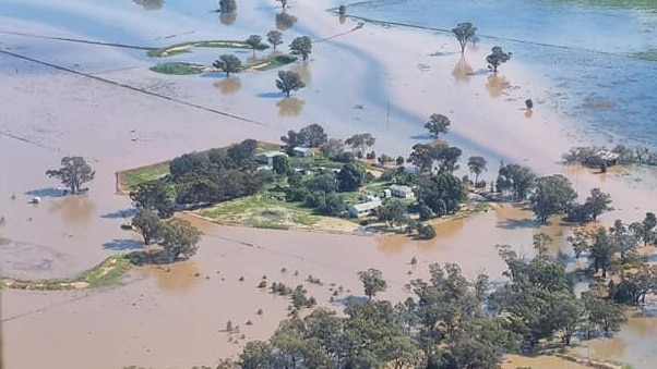 An aerial view of a small group of buildings not yet inundated by the surrounding floodwater.