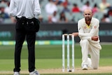 Australian bowler Nathan Lyon, on one knee, looks at the umpire in anguish.