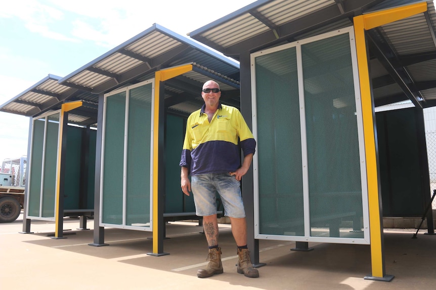 Grant Ryan stands in his work clothes near the new bus shelters