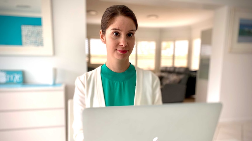 A brunette women looks at her computer in her home.