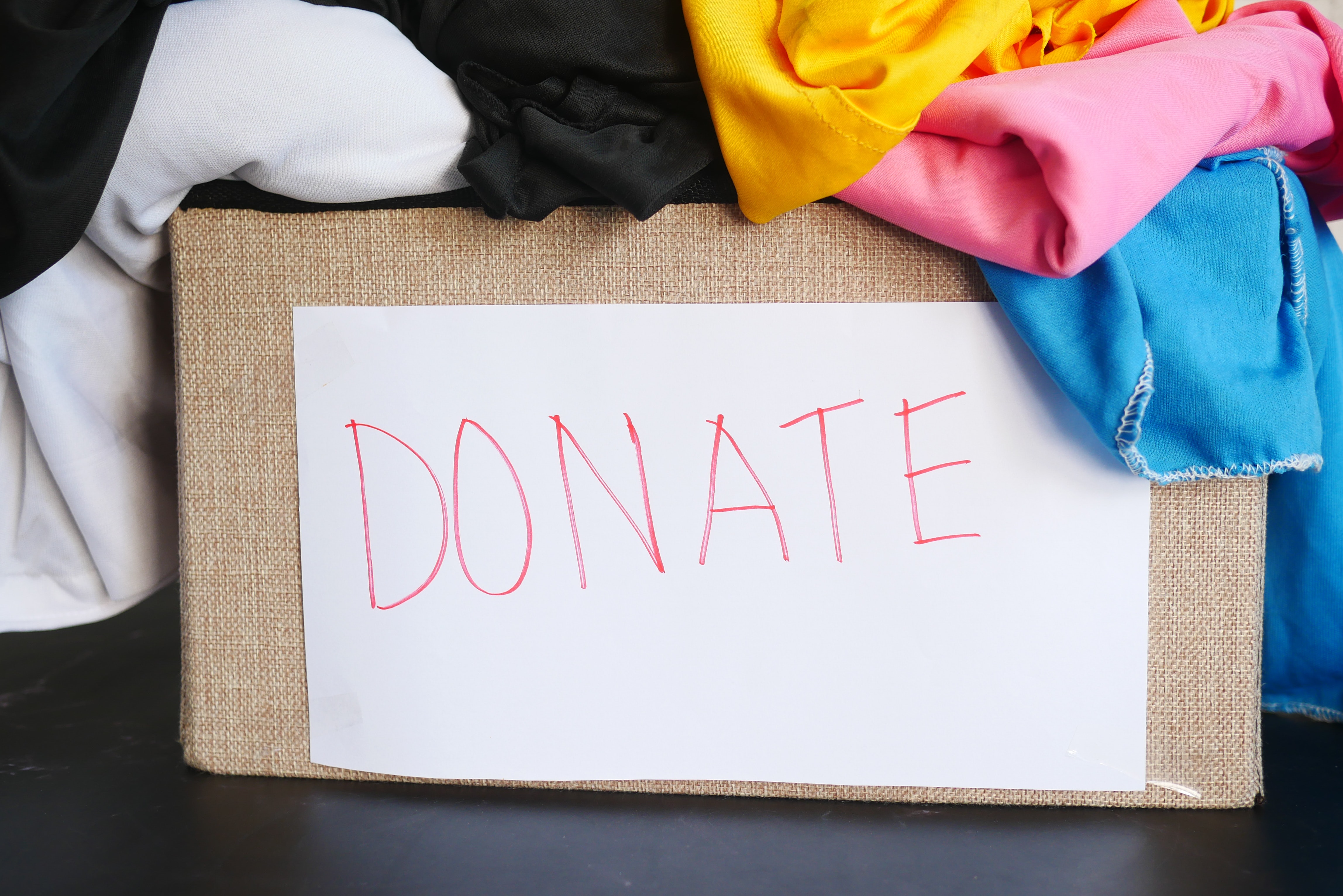 A box filled with clothes has a sign on the front with the word "donate".