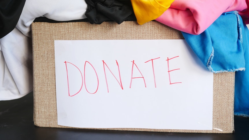 A box filled with clothes has a sign on the front with the word "donate".