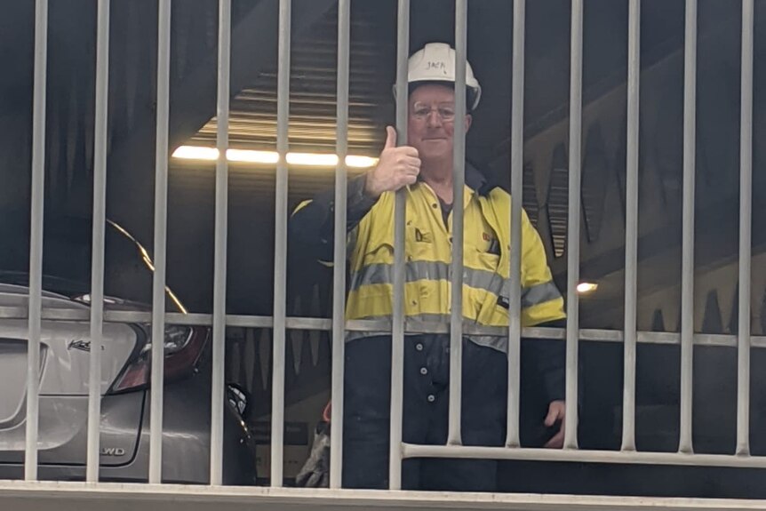A man in a high-vis yellow shirt and a hard hat in a multi-storey carpark