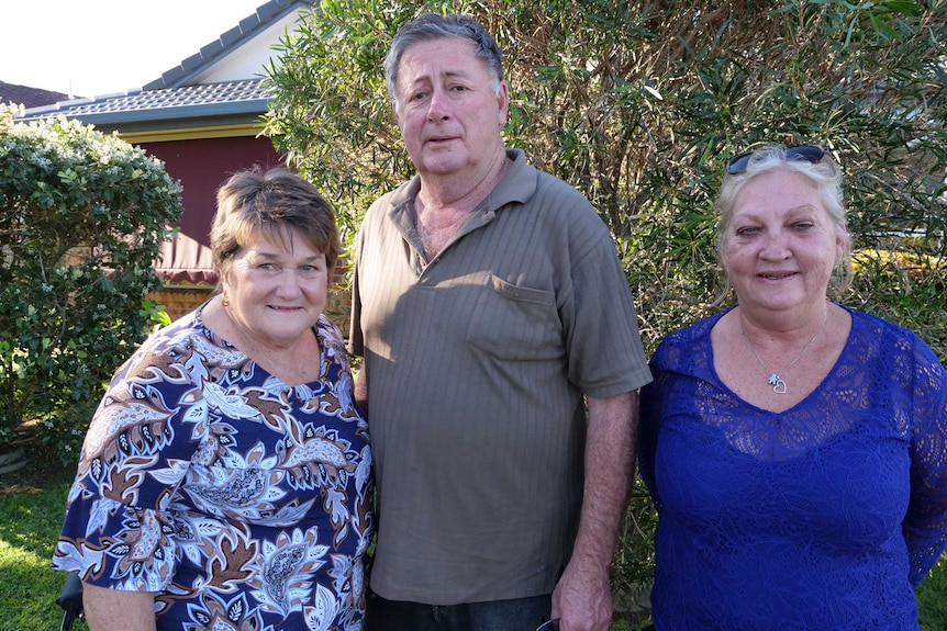 Joan and her husband Garry stand together and support worker Karren beside him in her home front garden