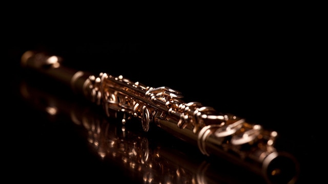 Gold flute on black background.