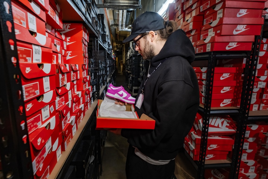 Jayden Traynor in storeroom with pink sneakers.
