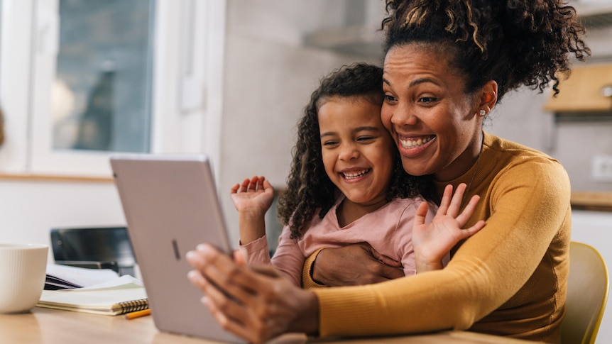 Mum and child video calling someone and smiling