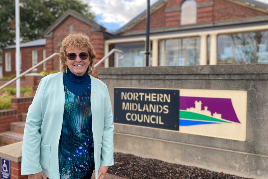 A woman wearing sunglasses stands next to a sign which reads Northern Midlands Council 