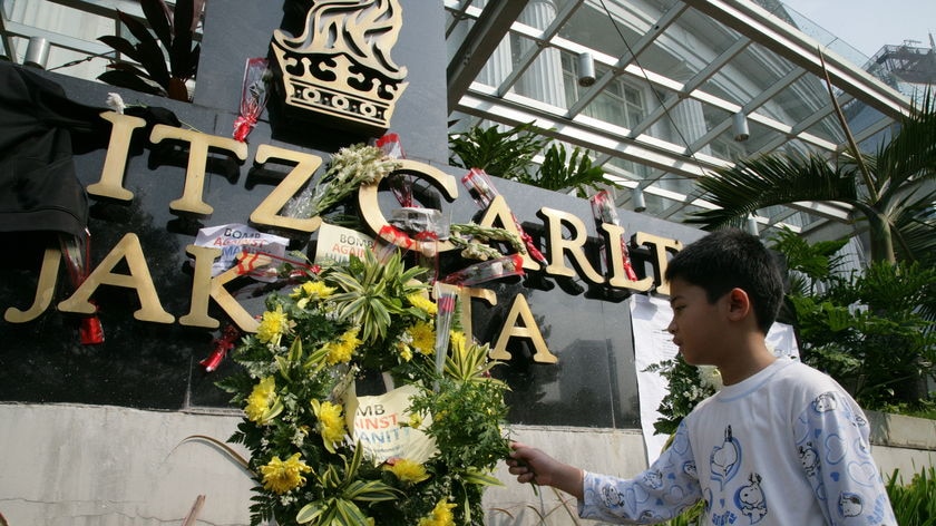 A boy places a flower on the Ritz-Carlton hotel sign in Jakarta on July 18, 2009.