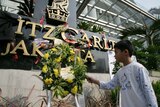 A boy places a flower on the Ritz-Carlton hotel sign in Jakarta on July 18, 2009.