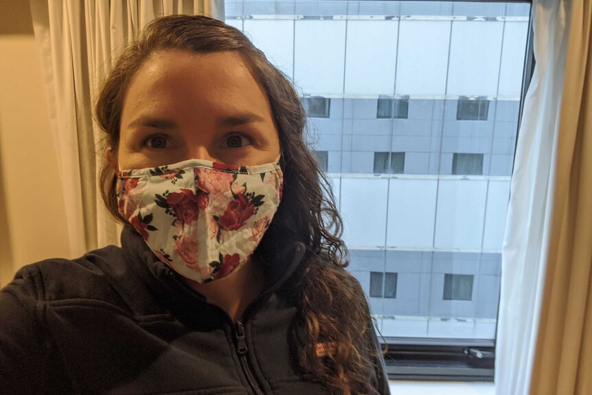 Lauren Farmer, wearing a cloth mask, taking a selfie in her quarantine hotel room.
