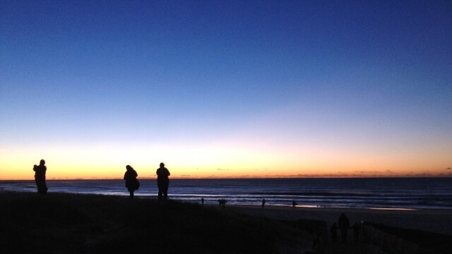 The sun rises over Newcastle's Nobbys Beach during the ANZAC Day dawn service.