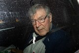 George Pell looks out car window