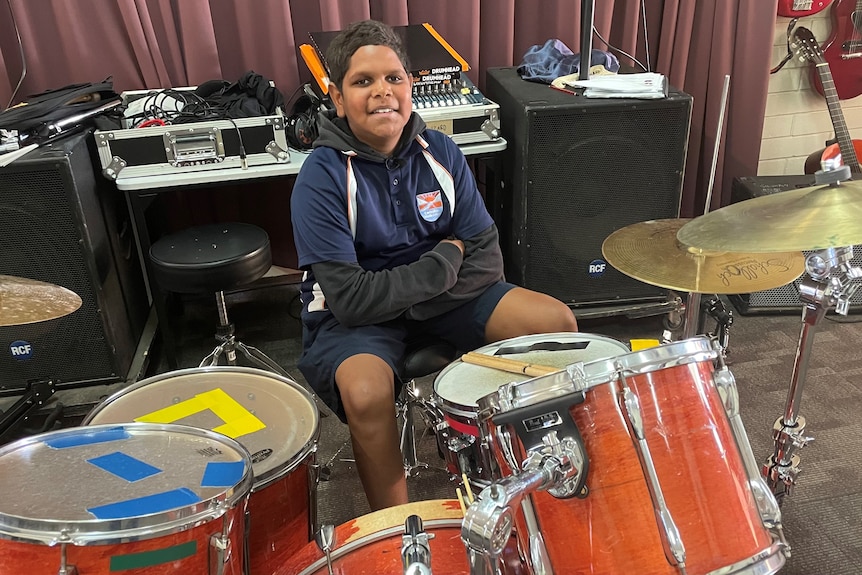 Smiling boy behind a drum kit.
