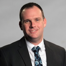 A man with short dark hair smiling in a professional photo 