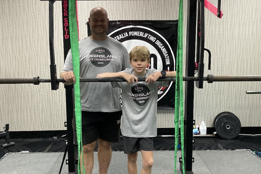A man and boy standing next to a gym machine