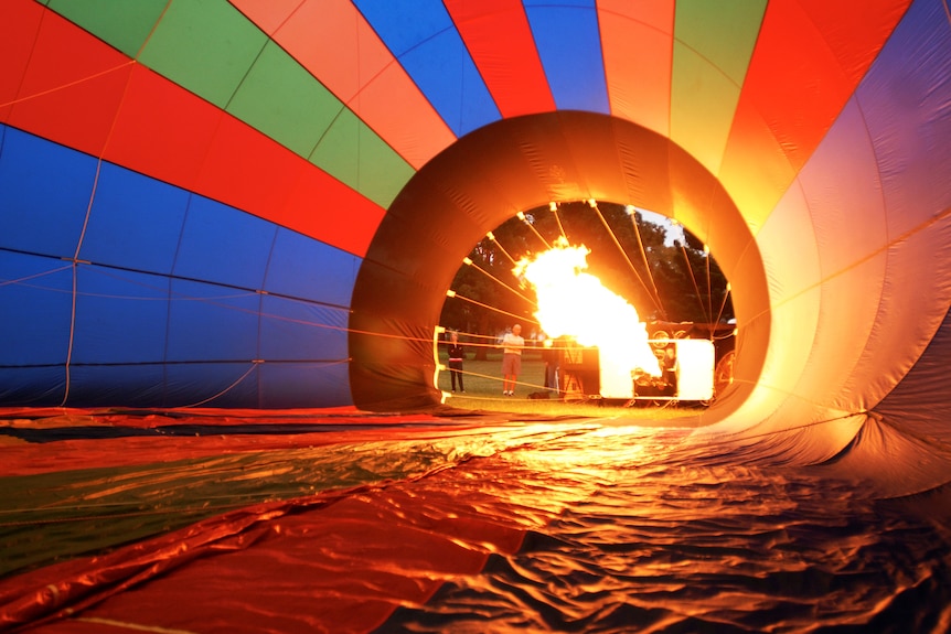 A blast of fire streams into the middle of a partially inflated hot air balloon.