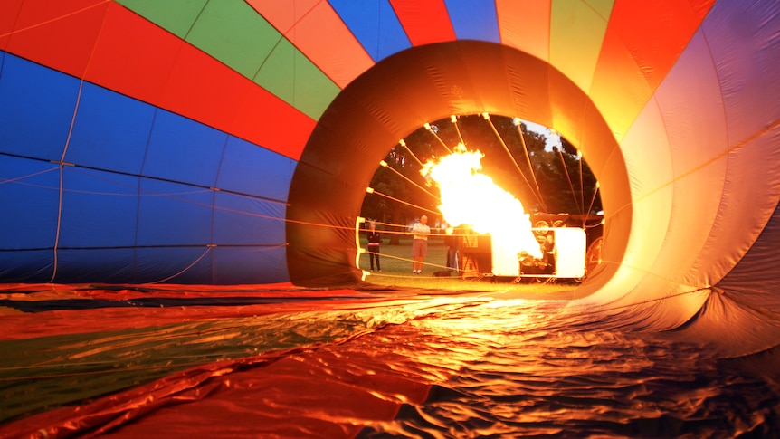 A blast of fire streams into the middle of a partially inflated hot air balloon.