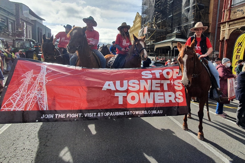 Personnes à cheval tenant une pancarte lisant "Arrêtez les tours AusNet"