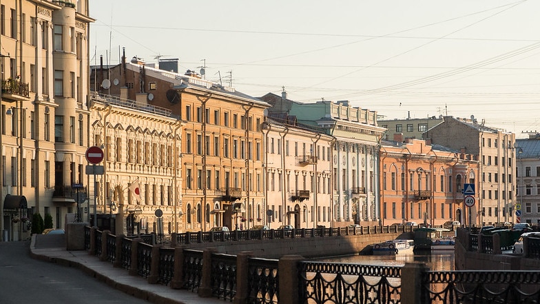 At first light, you view a quiet street by a canal in St Petersburg, which is lined by neoclassical buildings.