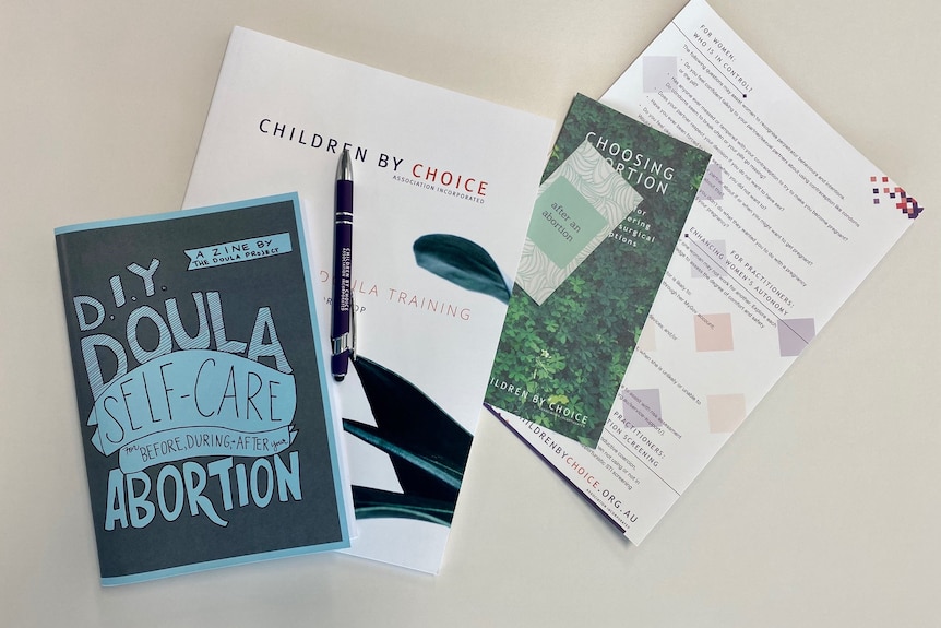 Top-down image of an selection of brochures on abortion doulas. The main leaflet is a zine titled DIY Doula Self Care.