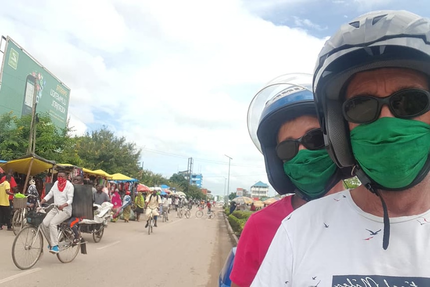 Craig and Del wear face masks on a scooter in Africa.