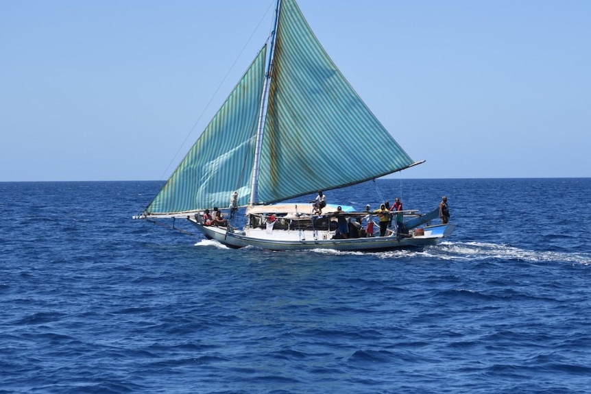 A boat with a white sail on the water