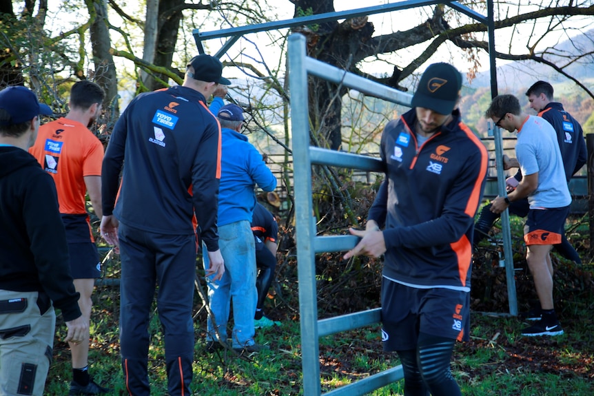 At least six men help clear damaged fencing at a property.