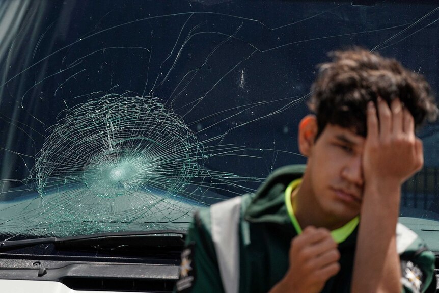 A St John Ambulance worker looks on in front of an ambulance windscreen, which had been smashed by an Ellyse Perry six.