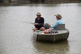 Two men fish from their tinny on the River Murray