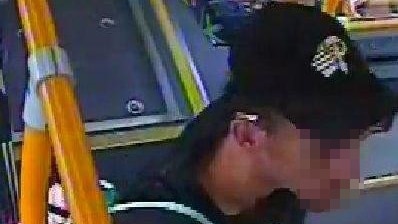 Grainy CCTV image of a man on a bus carrying a backpack.
