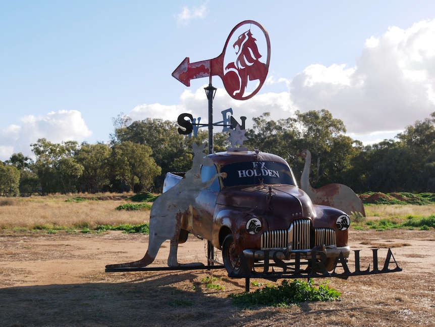 A dark brown ute with a steel emu on one side and a kangaroo on the other and a compass on top.