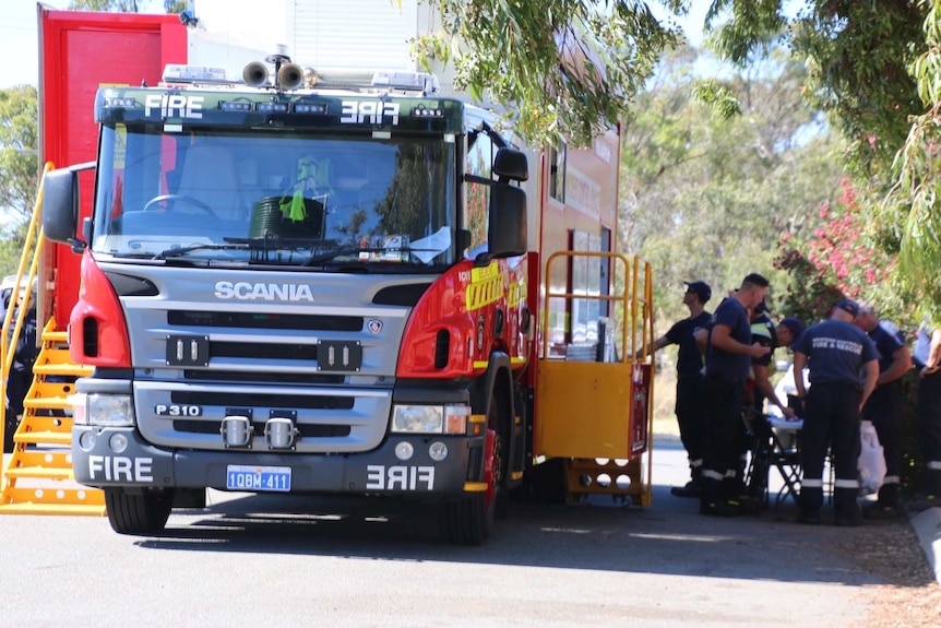 A fire truck with firefighters standing nearby.