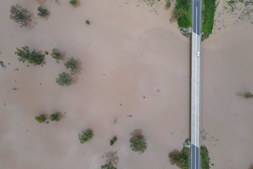 Car drives down highway above floodwaters