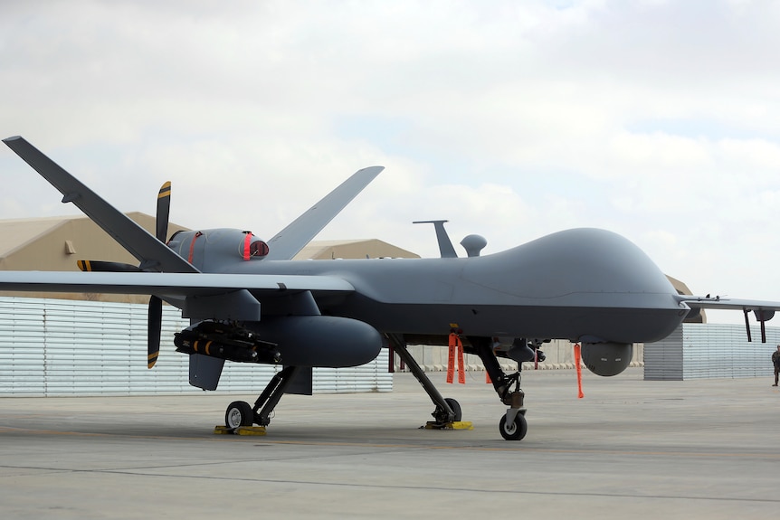 A large aerial drone with a dome at the front and a propeller at the back is on display during an air show.