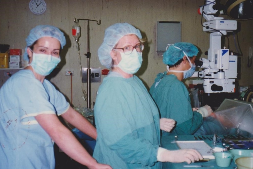 Two nurses wearing gowns and masks in an operating theatre