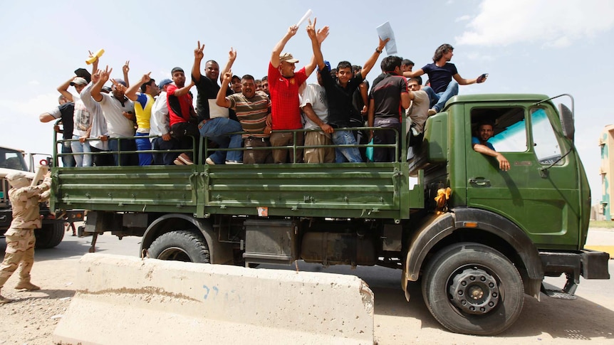 Volunteers who have joined the Iraqi army wave from a truck