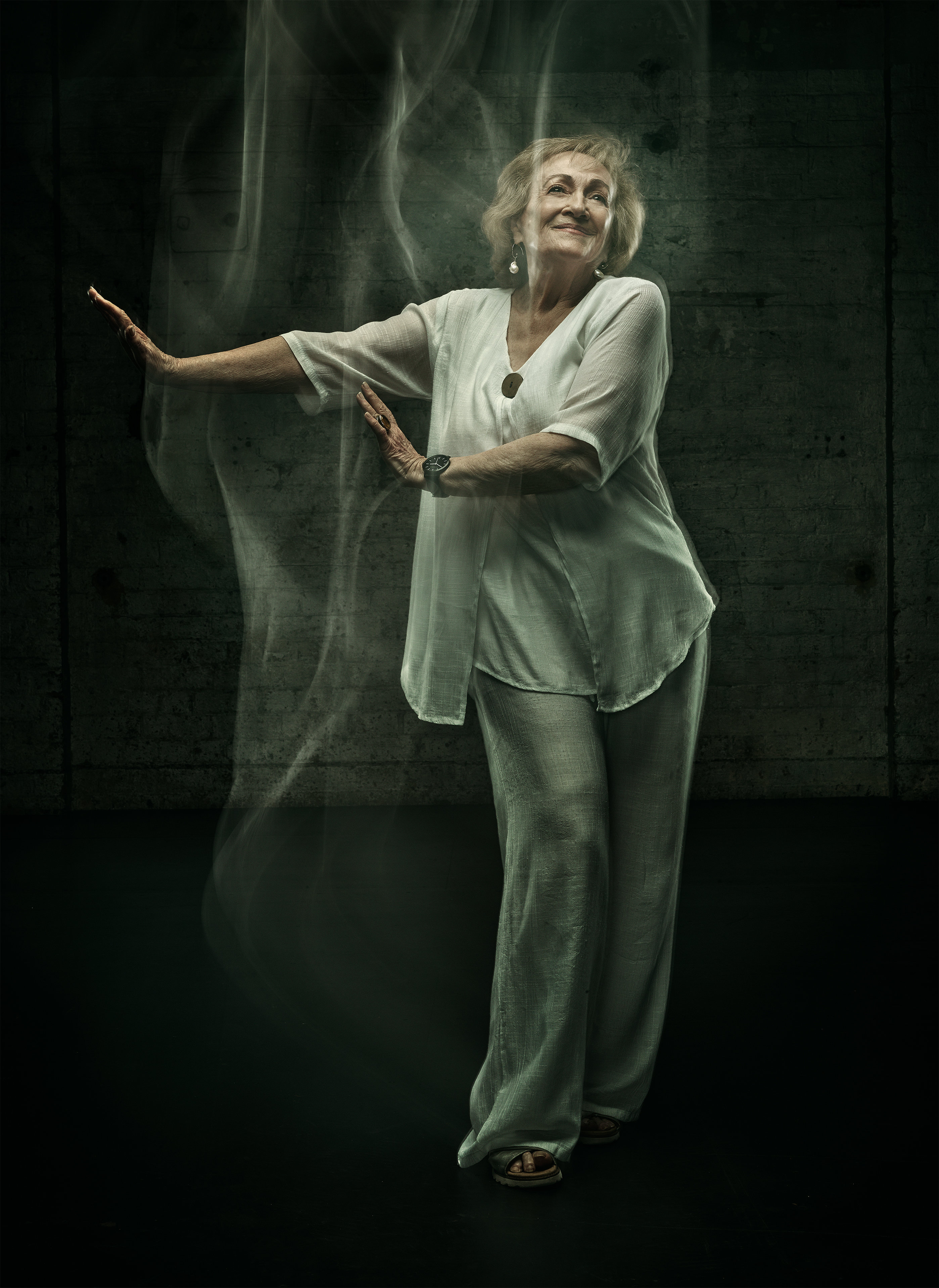 Older woman in white smiling and standing in a dance pose