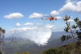 A Rural Fire Service helicopter water bombs a bushfire at Katoomba