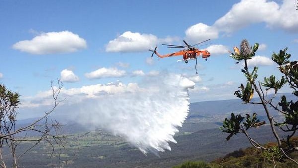A Rural Fire Service helicopter water bombs a bushfire at Katoomba