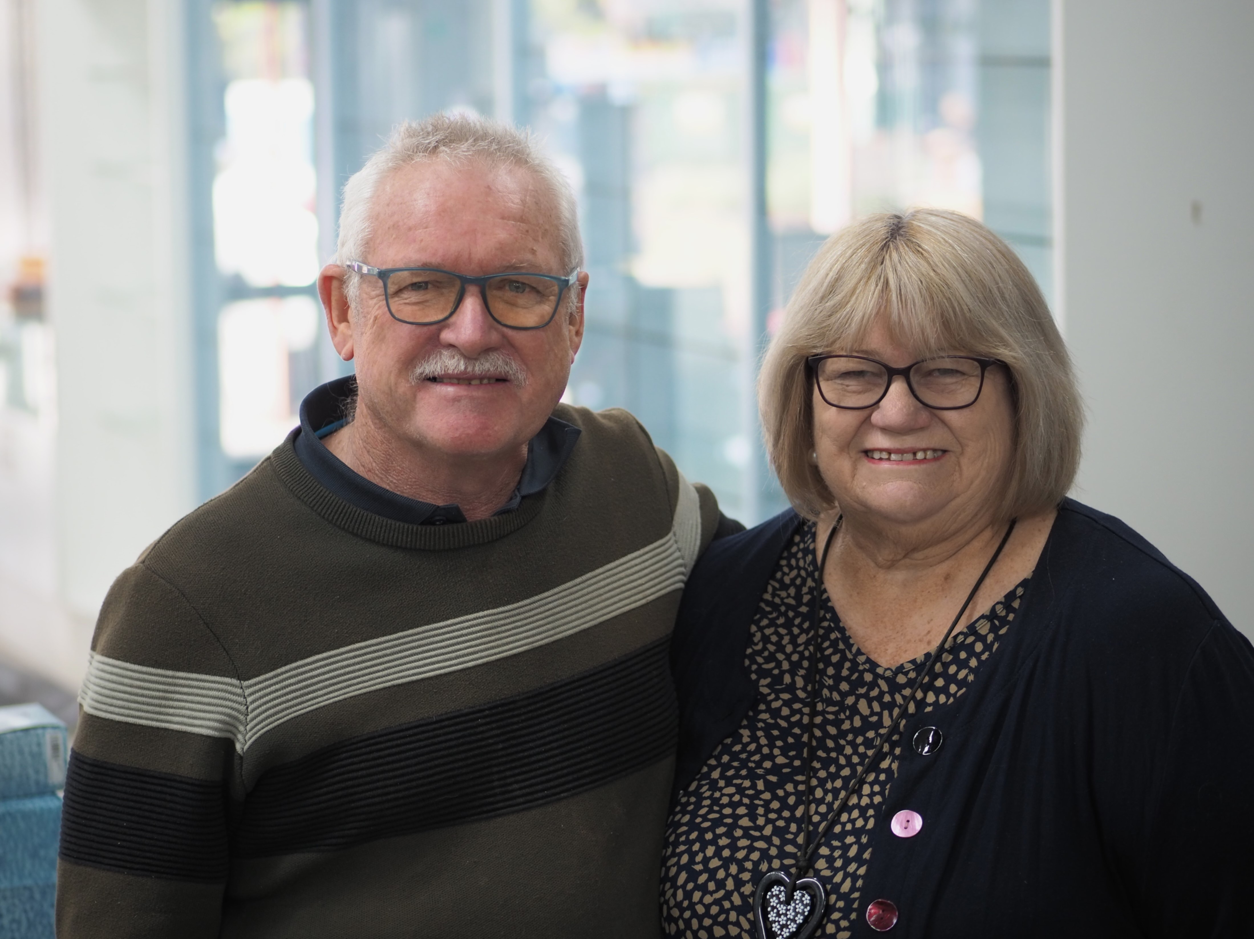 Un hombre y una mujer, en sus 70 años, en el brazo de pie frente a los estantes vacíos en su pequeña empresa