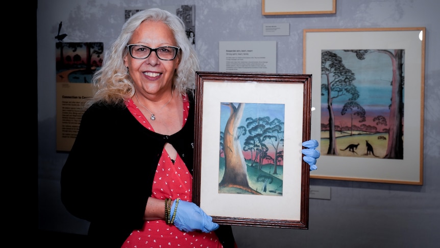 A woman holding a piece of Aboriginal art