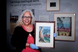 A woman holding a piece of Aboriginal art