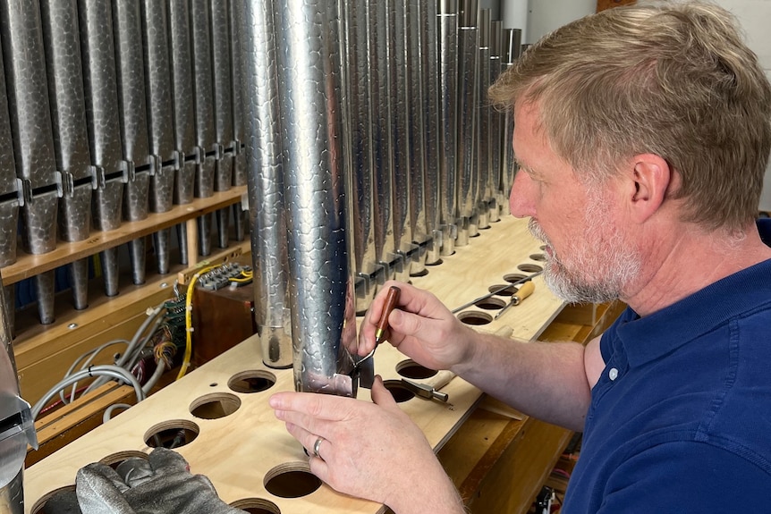 a worker at Dobson Pipe Organ Builders work on the pipes on the organ for st james' church in sydney
