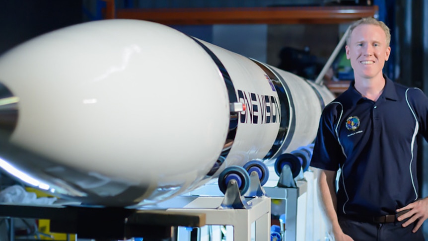 A man standing next to a rocket.