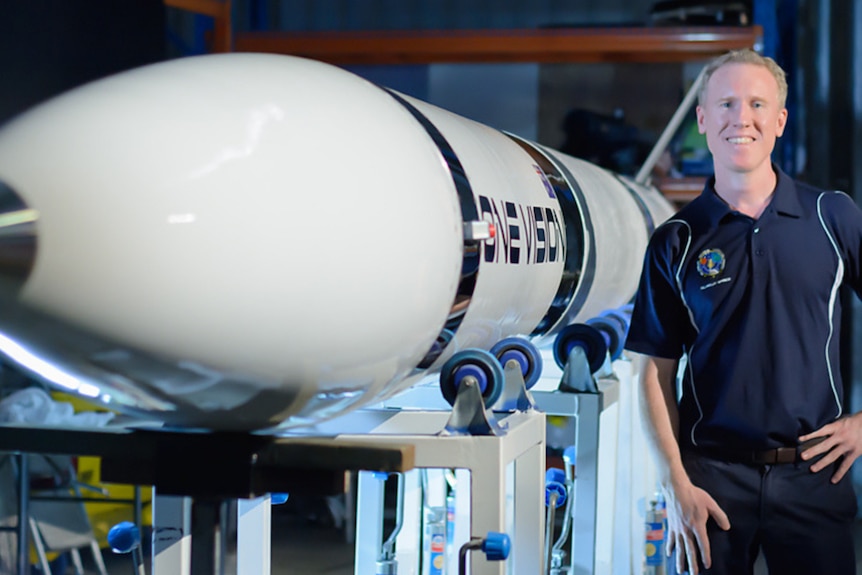 A man standing next to a rocket.